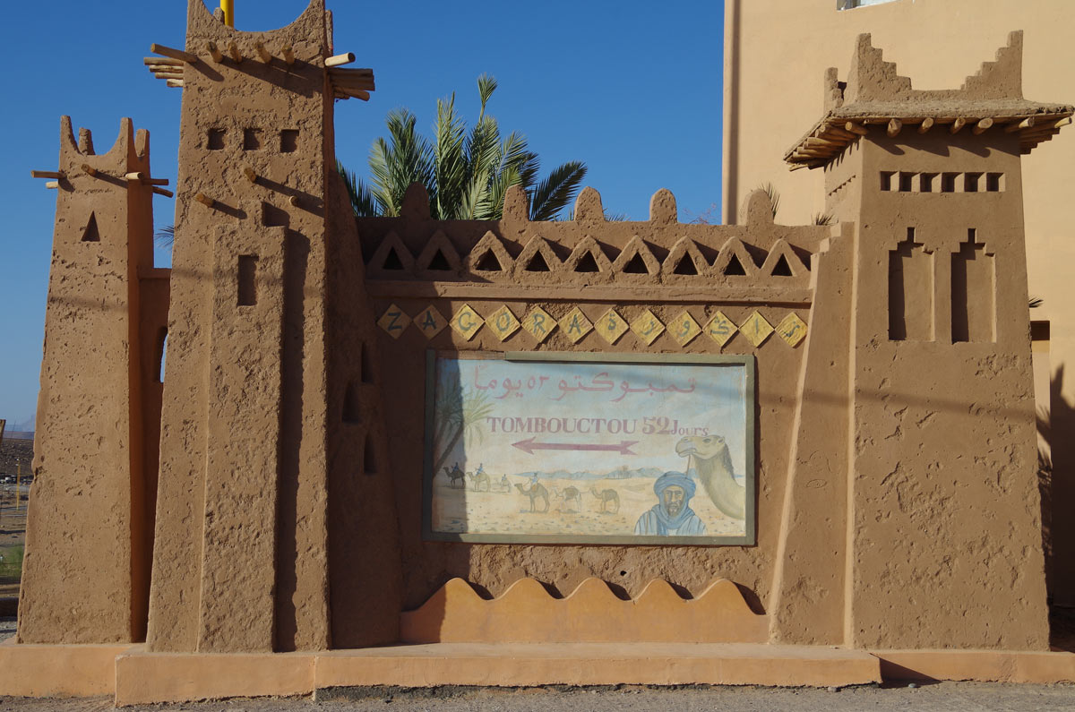 A gateway with a faded sign that says Tombouctou 52 Jours