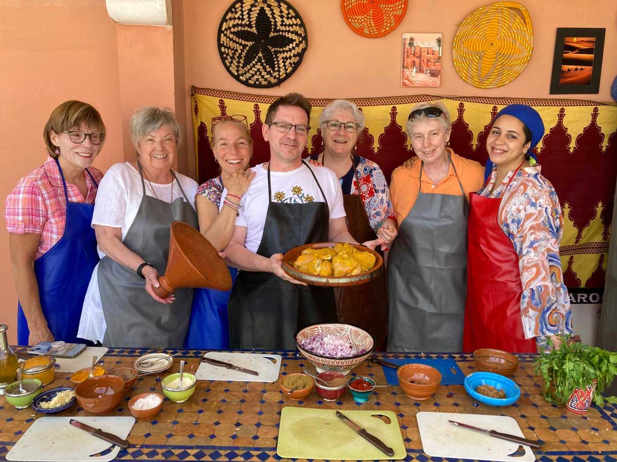 A group of students wearing aprons in front of a table of dishes they prepared