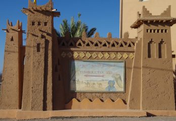 A gateway with a faded sign that says Tombouctou 52 Jours