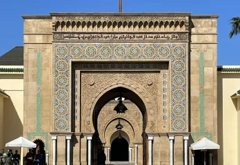 An elaborate stone palace gate with mosaic and with a red flag flying from the top