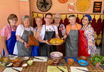 A group of students wearing aprons in front of a table of dishes they prepared