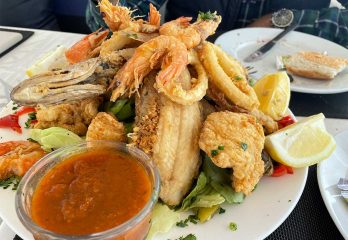 A plate piled high with fried fish, shrimp, and other seafood, accompanied by lemons and sauce